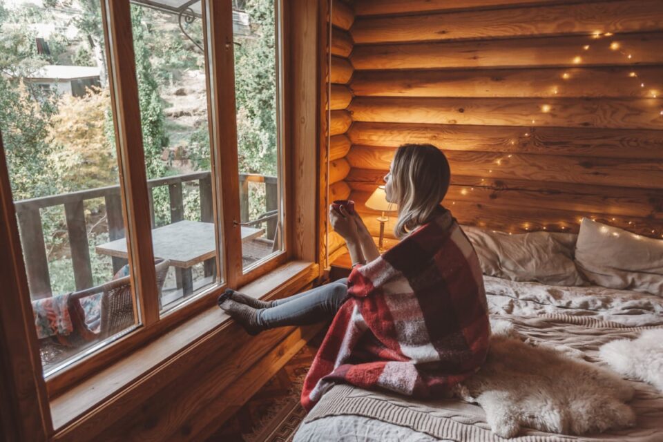 Woman with hot beverage in cozy cabin